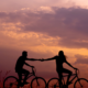 Dvojica na bicykloch sa drží za ruky