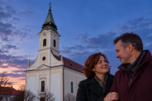 Dvojica pri kostole Najsvätejšej Trojice v Bánovciach nad Bebravou za súmraku, ilustračná AI fotografia