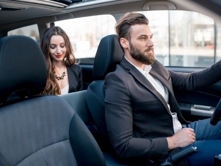 muž šoféruje auto a vzadu sedí atraktívna žena