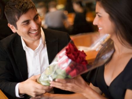 muž dáva v reštaurácii kyticu ruží