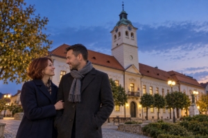 Dospelá dvojica pri budove Baníckeho múzea v Gelnici za súmraku, ilustračná AI fotografia
