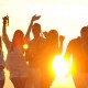 partia mladých ľudí sa zabáva na pláži pri západe slnka