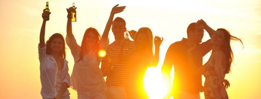 partia mladých ľudí sa zabáva na pláži pri západe slnka