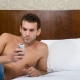 muž na posteli číta z mobilu