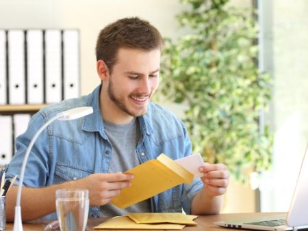 muž číta obálku a usmieva sa
