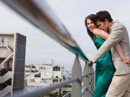 muž objíma ženu zozadu na balkóne