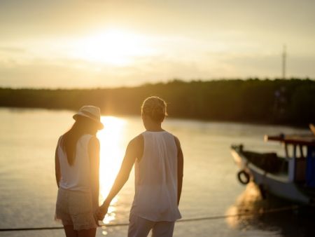 pár sa drží za ruku na brehu jazera