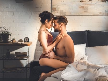 muž sedí na posteli a žena sedí na ňom obkročmo