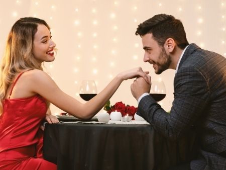 muž bozkáva žene ruku pri stole 