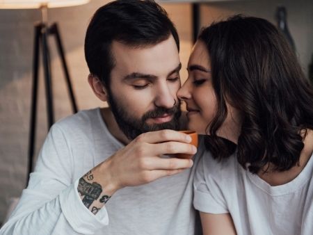 muž a žena sa dotýkajú nosami nad šálkou kávy