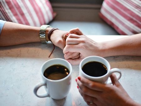 držiace sa ruky muža a ženy pri káve