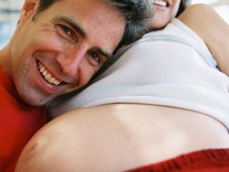 muž má tvár na ženinom tehotnom bruchu