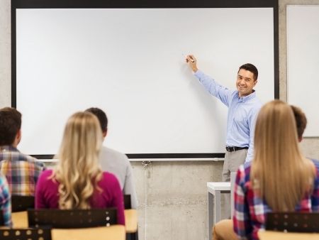 učiteľ v triede ukazuje na tabuľu