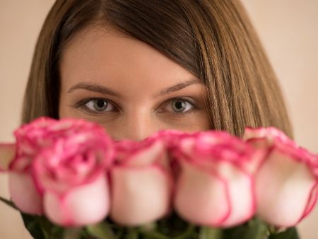 žene vidno len oči ponad ruže